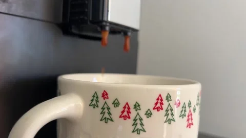 Coffee machine pouring espresso into a festive mug with holiday tree patterns Stock Footage 293985093