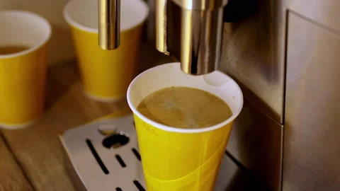 Coffee machine pours coffee into yellow paper cups, close-up process Stock Footage 172252029