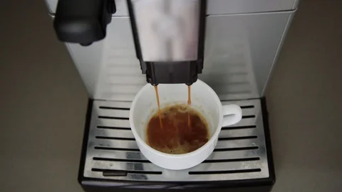 Coffee machine pours foaming beverage into cup on support Stock Footage 115398700