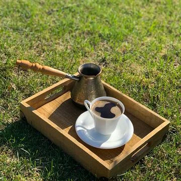 Coffee maker with a handle and a cup of coffee on a wooden tray. Stock Photos