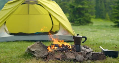 Coffee maker near the fire and tent in the forest glade Stock Footage 157183438