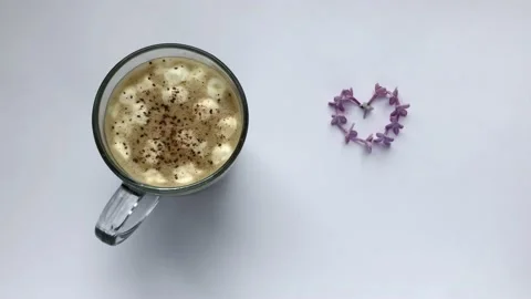 Coffee with marshmallows and cinnamon. Blows off heart-shaped lilac flowers Stock Footage 131745326