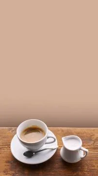 Coffee with milk in ceramic cup with small milk jug on old wooden window sill Stock Photos