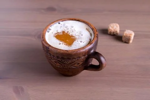 Coffee with milk in a fired earthenware mug with cane sugar pieces Stock Photos