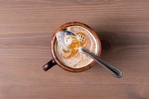 Coffee with milk in a fired earthenware mug with a small spoon. Stock Photos