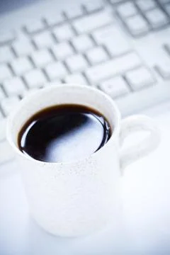 Coffee mug and computer keyboard Foto stock