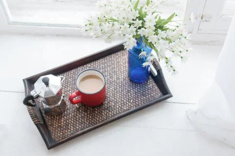 Coffee mug, coffee maker with white flowers bouquet on tray Stock Photos