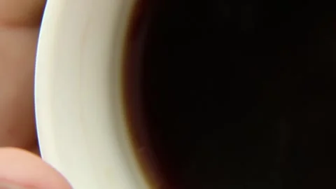 Coffee mug with fragrant coffee in a person's hand. Hot drink with steam Stock Footage 242502027