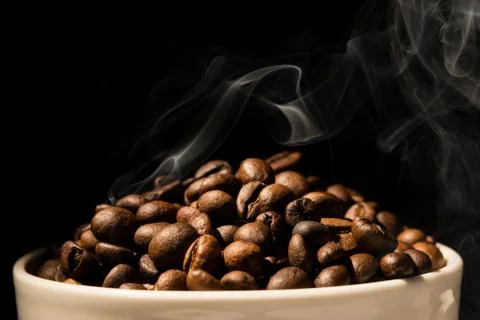 Coffee mug full of coffee beans with smoke Fotos de archivo
