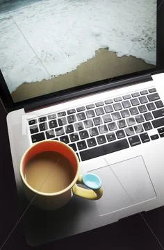 Coffee Mug On Laptop Computer With Beach On Screen