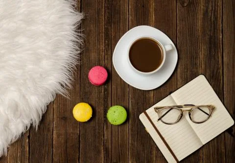 Coffee mug, macarons, notebook and glasses on a wooden table. Top view Stock-Fotos