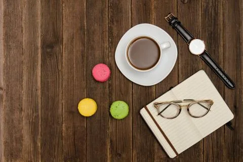 Coffee mug, macarons, watch, notebook and glasses on a wooden table. Side vie Fotos Stock