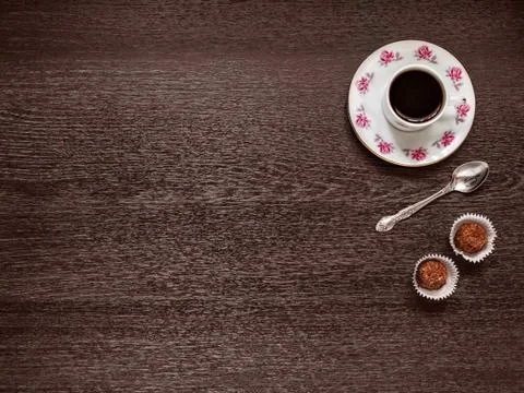 Coffee mug on a saucer, a teaspoon, two candies on a wooden background Stock Photos