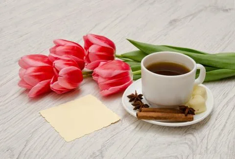 Coffee mug with spices, clean note, pink tulips on a wooden background, sprin Stockfoto's