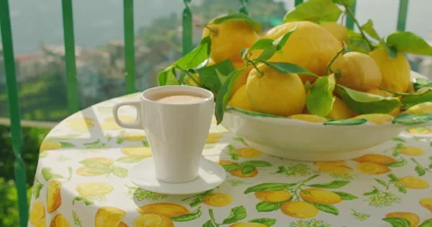 Coffee mug on a table with a bowl of lemons bathed in sunlight. The morning's Stock Footage 273295600