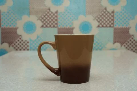 Coffee mug on a table with a colorful background featuring patterns Stock Photos