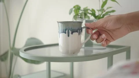 Coffee mug on a table with plants in the background Stock Footage 337522385
