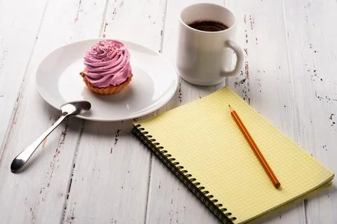 Coffee, pink cake and notepad on white wood table 写真素材