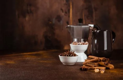 Coffee pot with spices on brown background. Stock Photos