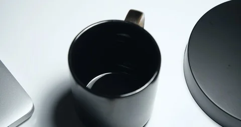 Coffee pour into black mug on simple white table close up Stock Footage 103239632