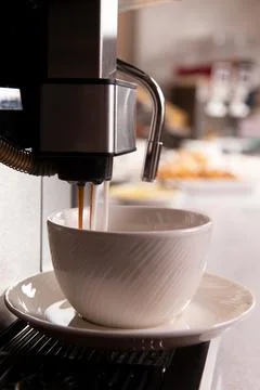 Coffee is poured into a cup from an automatic coffee machine. Stock Photos