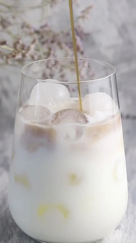 Coffee is poured into milk. Brown is mixed with white. Vertical video Stock Footage 160815476