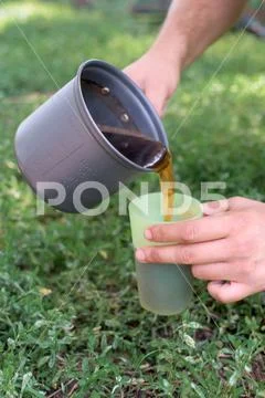 Coffee is poured from a pot into a glass in nature. picnic Stock Photos