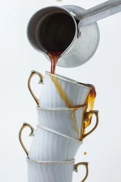 Coffee is poured into a stack of coffee cups. Boiled coffee on a white backgroun Stock Photos
