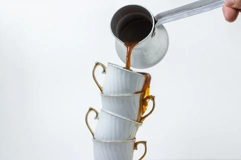 Coffee is poured into a stack of coffee cups. Boiled coffee on a white backgroun Stock Photos
