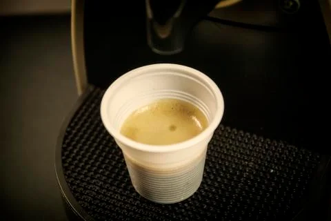 Coffee pouring from brewing machine into plastic cup Stock Photos