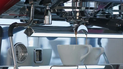 Coffee pouring into white ceramic cups from coffee machine Vídeos de archivo 77423375