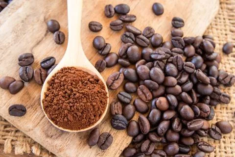 Coffee powder in wooden spoon and coffee beans on wooden table 스톡 사진