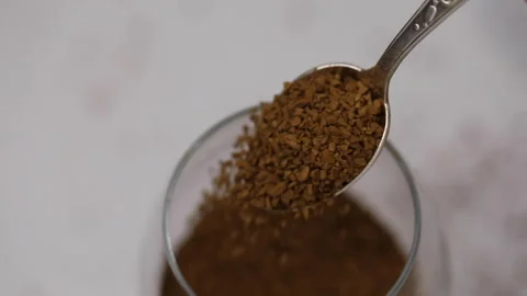 Coffee preparation process, instant coffee is poured from a spoon into a glass Stock Footage 147939406