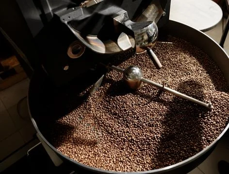 Coffee processing. Roastery, roasting machine and fresh beans Stock Photos