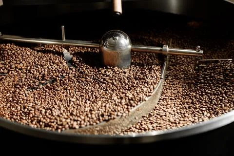 Coffee processing. Roastery, roasting machine and fresh beans Stock Photos