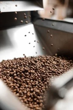 Coffee processing. Roastery, roasting machine and fresh beans Stock Photos