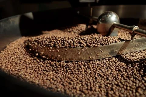 Coffee processing. Roastery, roasting machine and fresh beans Stock Photos