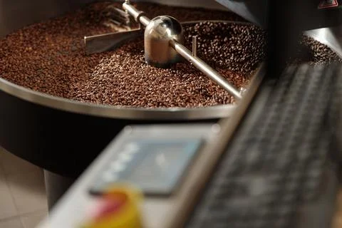 Coffee processing. Roastery, roasting machine and fresh beans Stock Photos