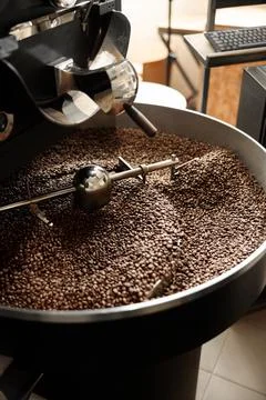 Coffee processing. Roastery, roasting machine and fresh beans Stock Photos