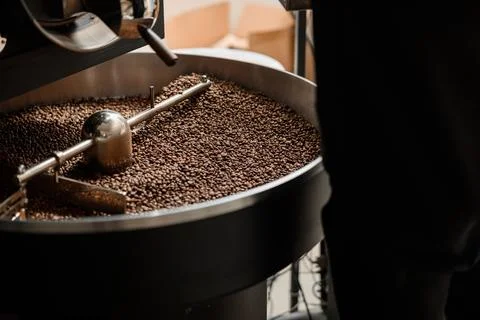 Coffee processing. Roastery, roasting machine and fresh beans Stock Photos