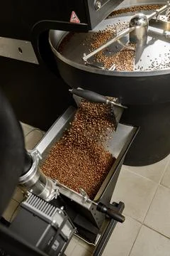 Coffee processing. Roastery, roasting machine and fresh beans Stock Photos