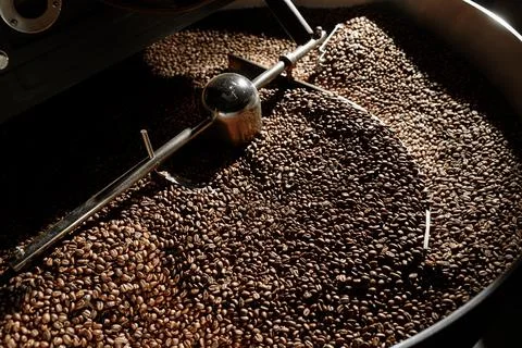Coffee processing. Roastery, roasting machine and fresh beans Stock Photos