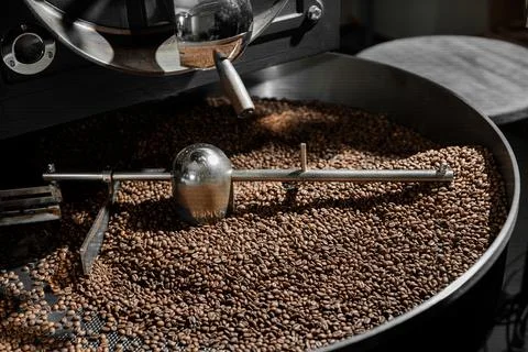 Coffee processing. Roastery, roasting machine and fresh beans Stock Photos