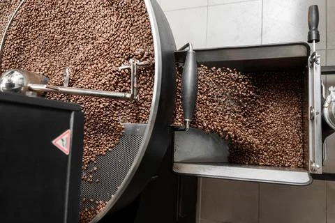 Coffee processing. Roastery, roasting machine and fresh beans Stock Photos