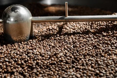 Coffee processing. Roastery, roasting machine and fresh beans Stock Photos