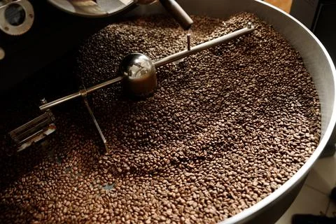 Coffee processing. Roastery, roasting machine and fresh beans Stock Photos