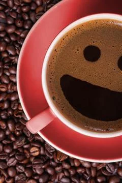 Coffee in red cup on a table surrounded by coffee beans. Coffee in the shape  Stock Photos