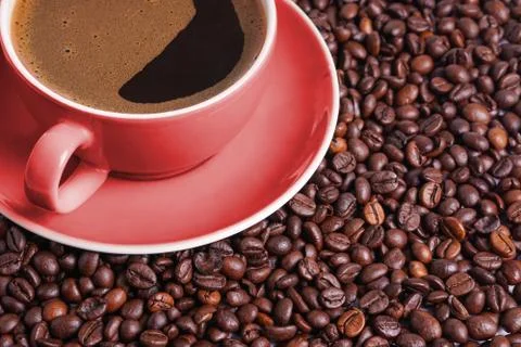 Coffee in red cup on a table surrounded by coffee beans. Foto stock