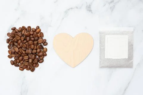 Coffee roasted beans, drip pack and empty wooden heart on marble background. Top Stock Photos