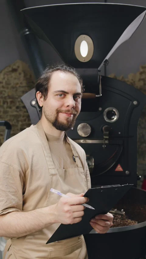 Coffee roaster assesses beans in a workshop at an artisanal coffee roasting Stock Footage 321765857
